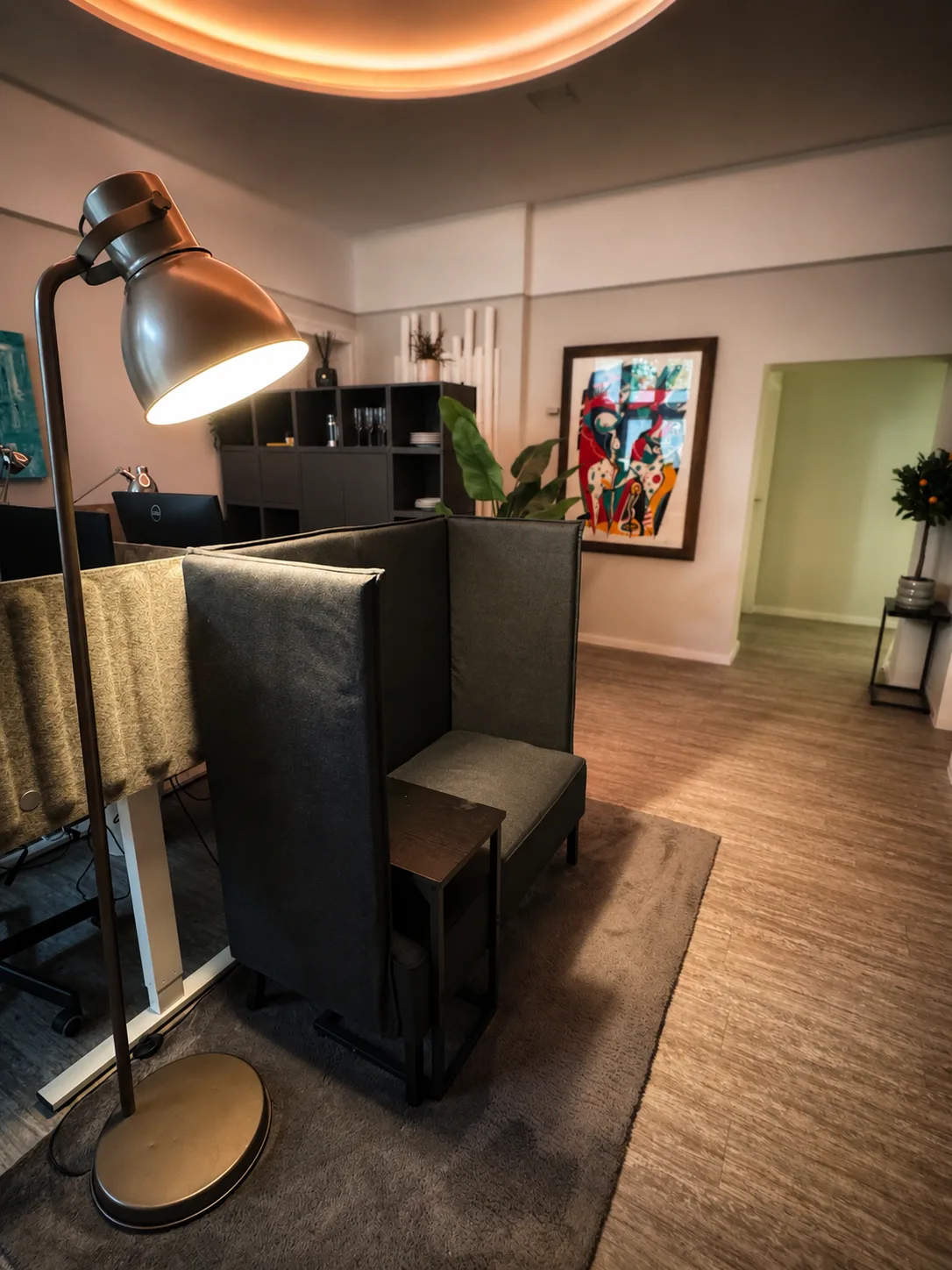 Arbeitsplätze im Hauptraum von Flexovo Tempelhof mit Stehlampe, Sichtschutz-Sessel, Schreibtischen und Kunst