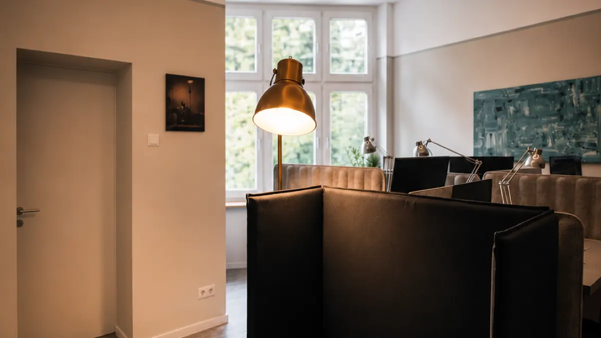 Flexdesk-Arbeitsplatz mit Sichtschutz-Lounge, Tageslicht-Fenster und Architektenlampe bei Flexovo Tempelhof